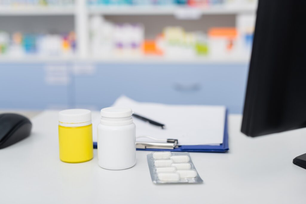 bottles and blister pack with medication near blurred clipboard